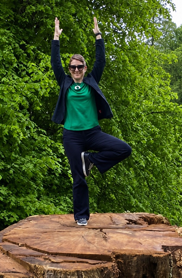 Jennifer Ellis smiling while practising tree pose outdoors